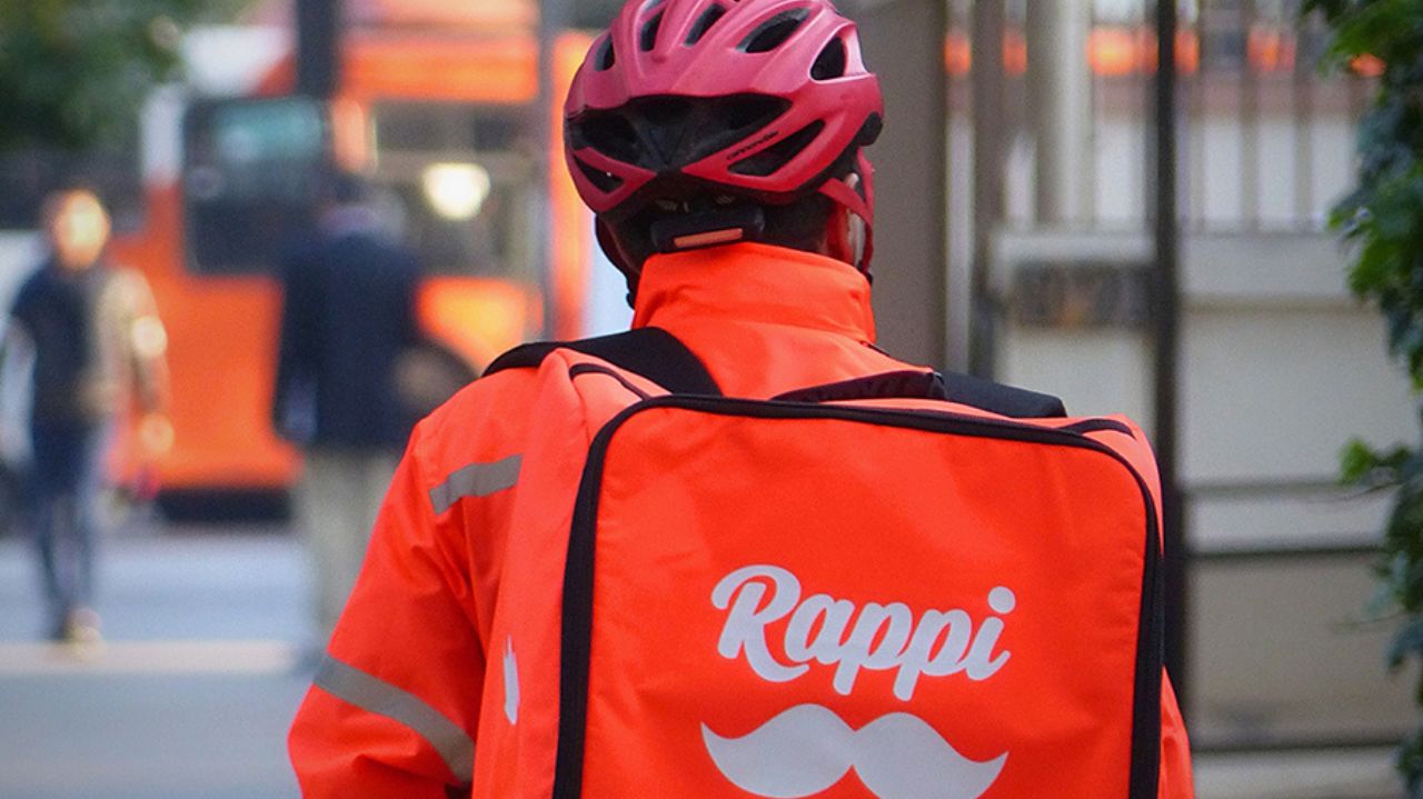 Entregador com capacete rosa e mochila da Rappi