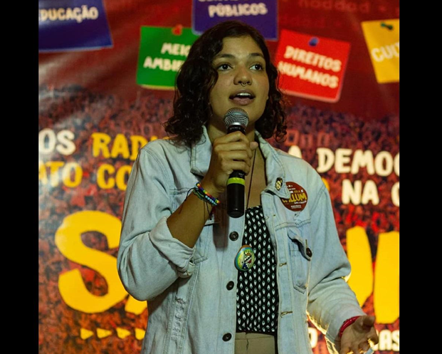 Duda Hidalgo falando em microfone