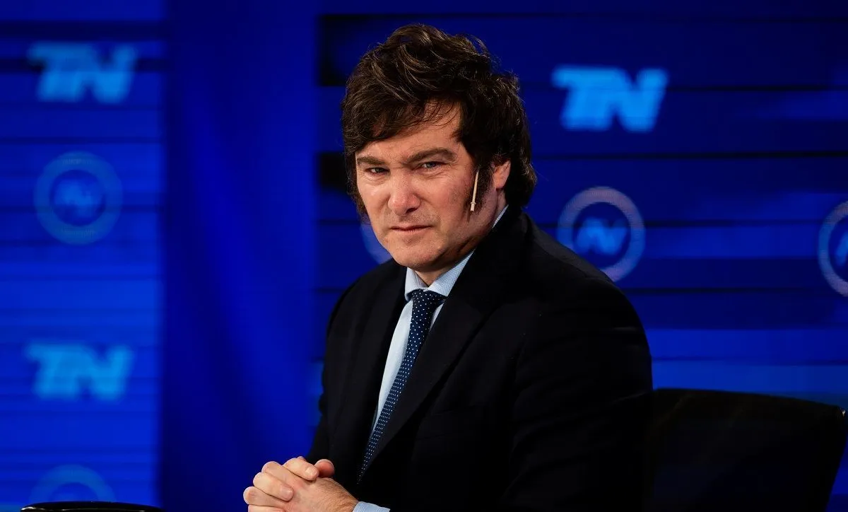 Javier Milei de terno e gravata, com mãos unidas e expressão séria