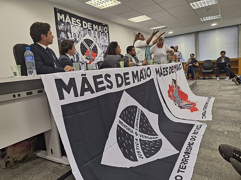 Imagem de encontro sobre direitos humanos, com cartazes das Mães de Maio