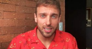 Léo Lins de camisa vermelha estampada, falando com expressão de preocupação