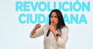 Luisa González falando em microfone e gesticulando, com expressão séria