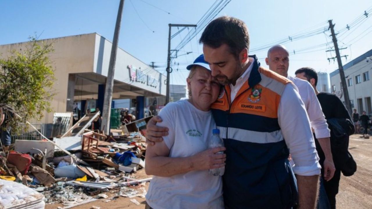 Eduardo Leite abraçando idosa em meio aos estragos causados por ciclone na cidade de Roca Sales