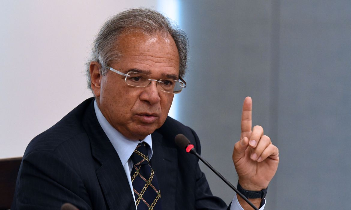 Paulo Guedes falando, de óculos, apontando pra cima
