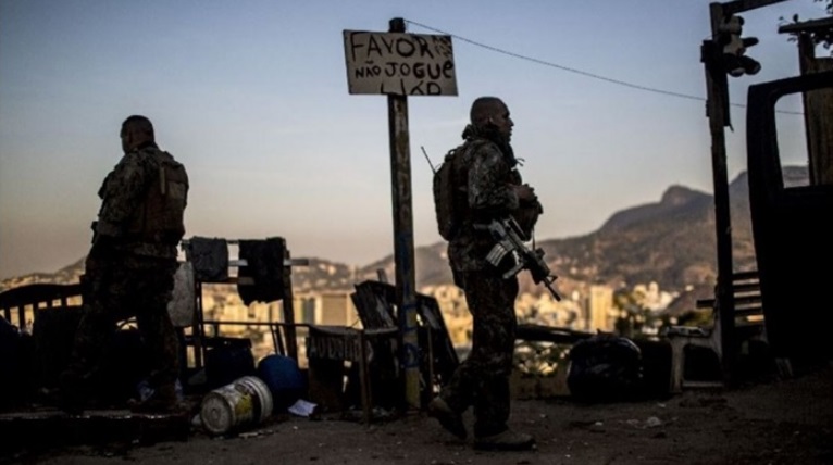 Homens fardados com armas perto de local com lixo
