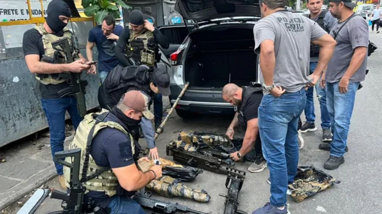 Policiais mexendo em armas que estão no chão