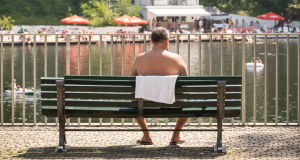 Homem sem camisa, de costas, sentado em banco