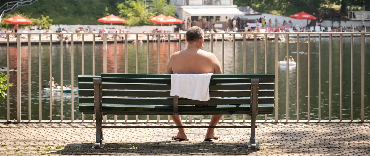 Homem sem camisa, de costas, sentado em banco