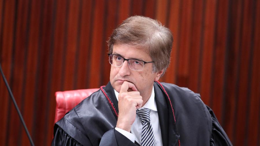Paulo Gonet com expressão séria, usando óculos e apoiando cabeça na mão