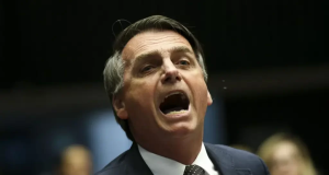 Jair Bolsonaro de terno e gravata, gritando