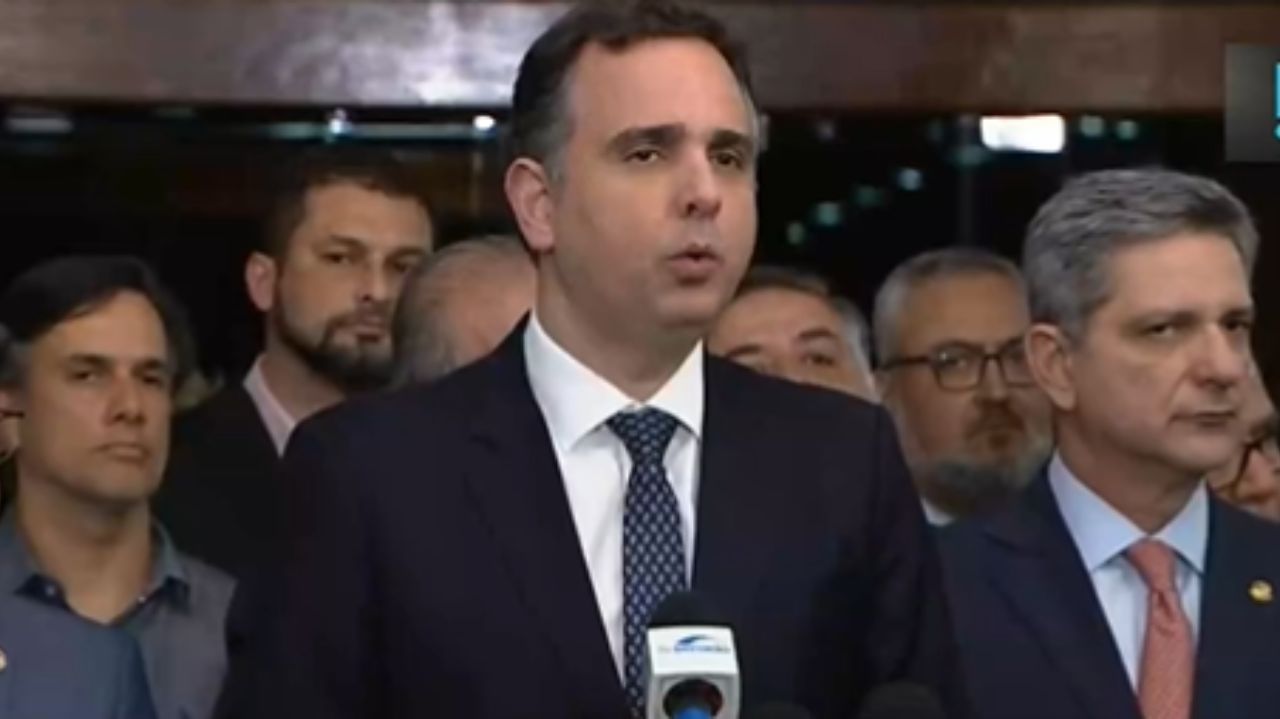 Rodrigo pacheco falando em microfone, rodeado de pessoas