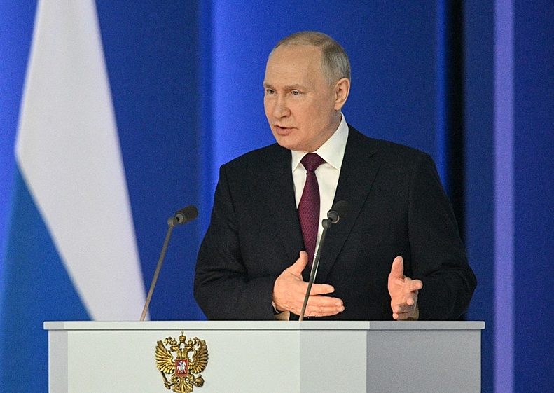 Vladimir Putin falando em microfone, com roupa social