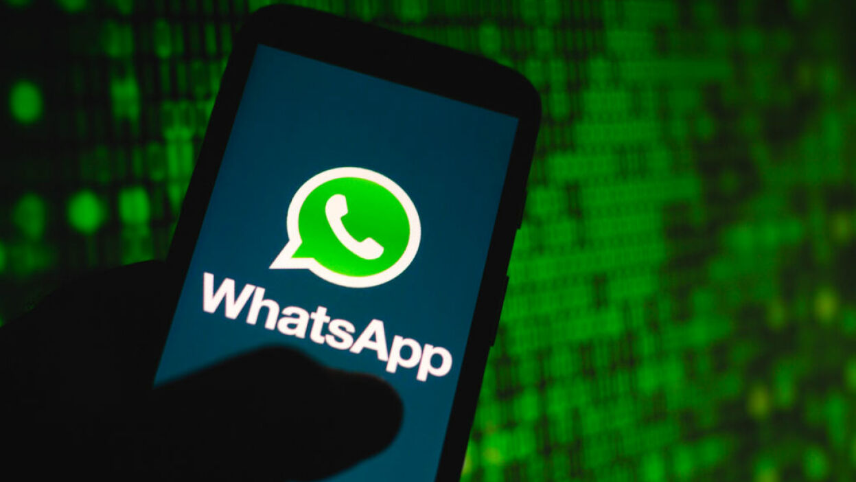 Mão segurando celular com logo de WhatsApp