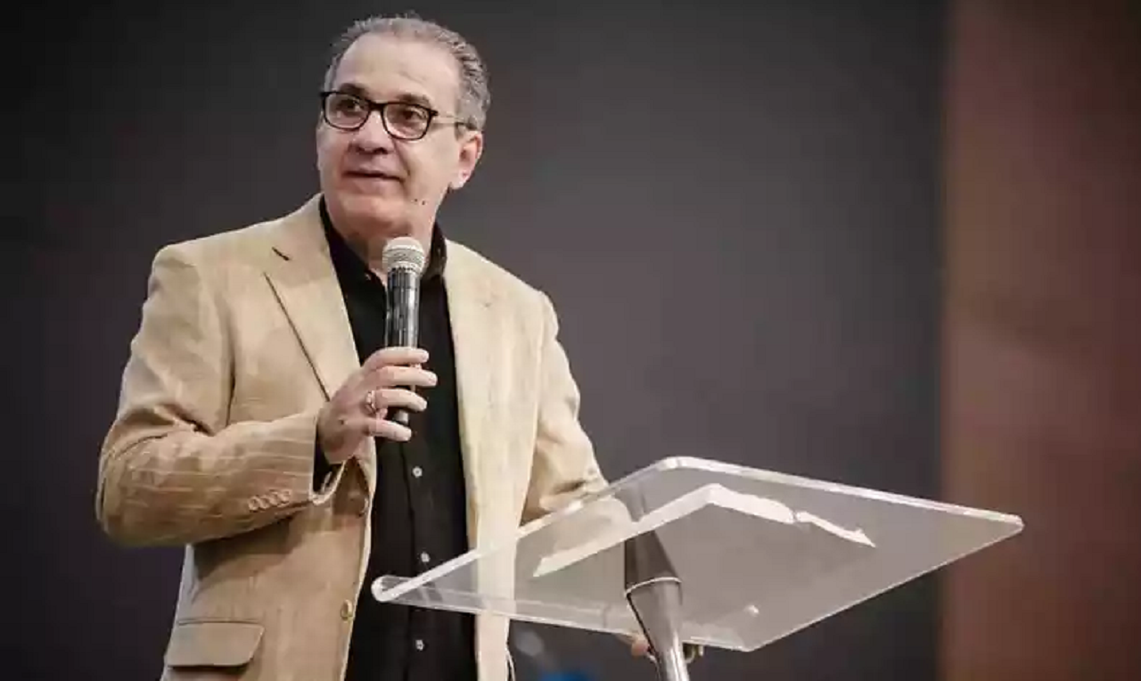 Silas Malafaia de roupa bege e preta, falando em microfone e olhando para o lado