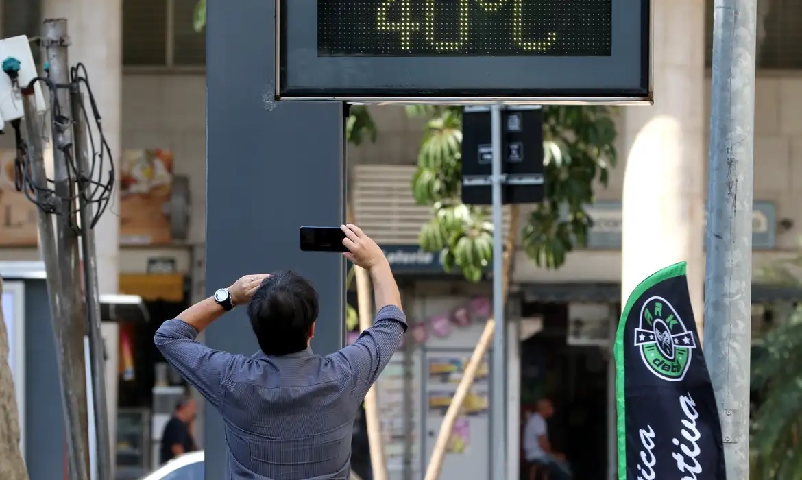 Homem fotografando relógio marcando 40 graus