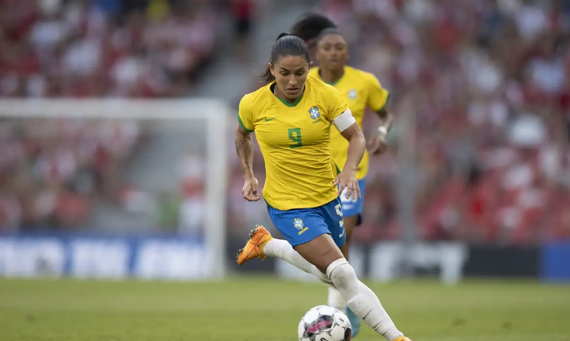 Debinha correndo em campo com uniforme da seleção brasileira