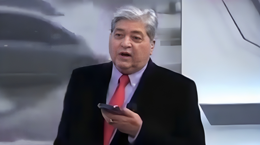 Datena no cenário do Brasil Urgente, segurando celular, com expressão de decepção