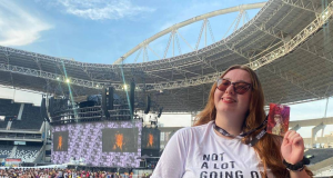 Mariana Marcarini no show que Taylor Swift fez no último dia 17, sorrindo e mostrando crachá em arquibancada