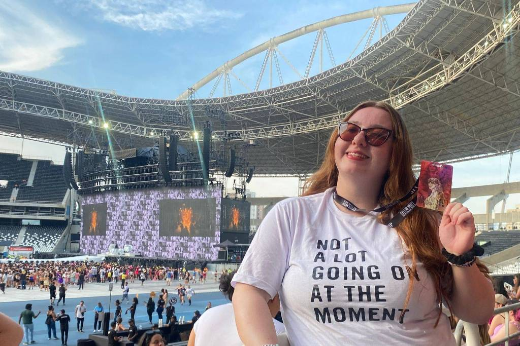 Mariana Marcarini no show que Taylor Swift fez no último dia 17, sorrindo e mostrando crachá em arquibancada