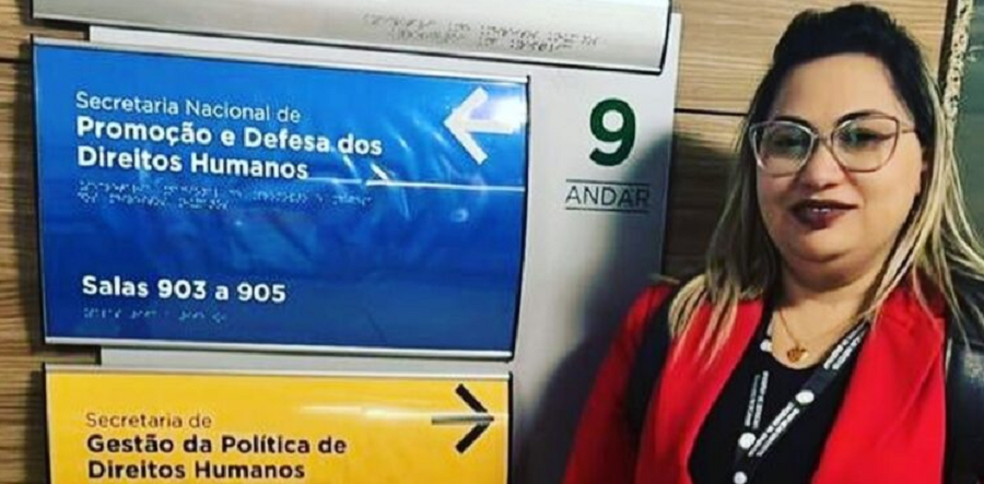 Luciane Barbosa Farias posando e sorrindo perto de placas