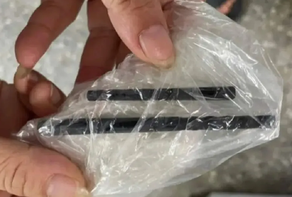 Mãos segurando dois pauzinhos envolvidos em plástico