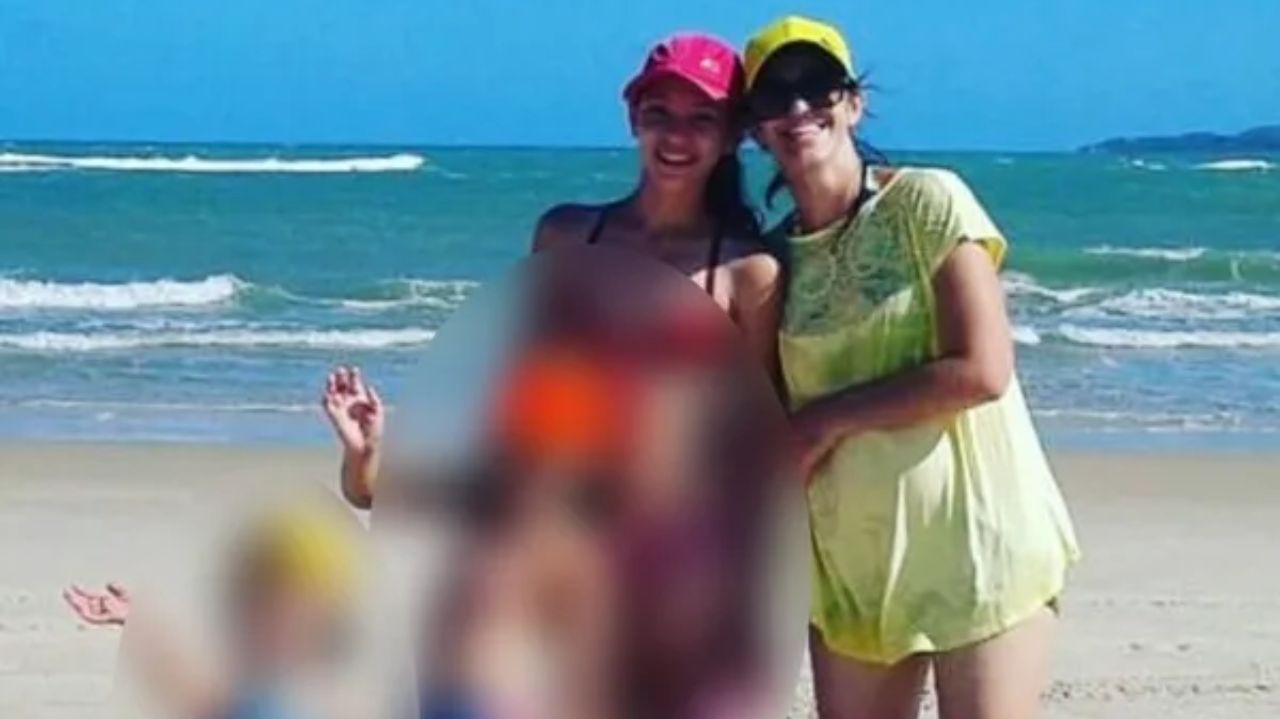 Mãe e filhas em foto na praia, crianças com imagens borradas