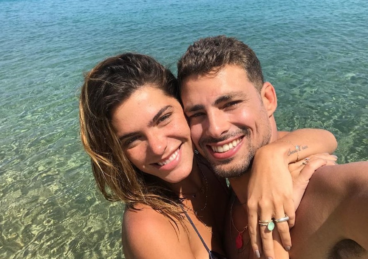 Mariana Goldfarb e Cauã Reymond abraçados e sorrindo em praia