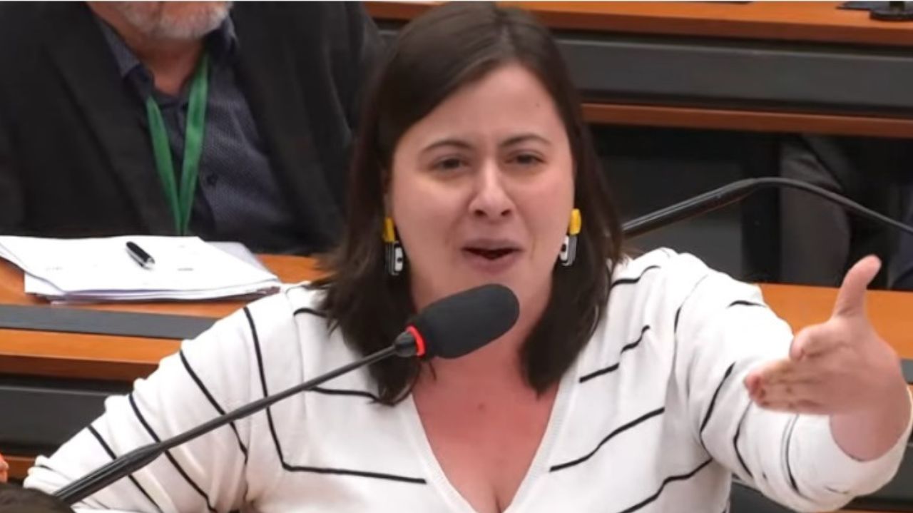 Sâmia Bomfim de roupa listrada preta e branca, falando e gesticulando
