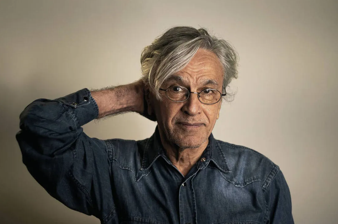 Caetano Veloso com mão na nuca e camisa jeans, sem sorrir