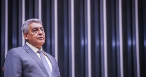 Sebastião Melo falando, com expressão de desânimo, e roupa formal cinza