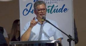 Fábio Pietro de roupa clara e óculos, falando e gesticulando
