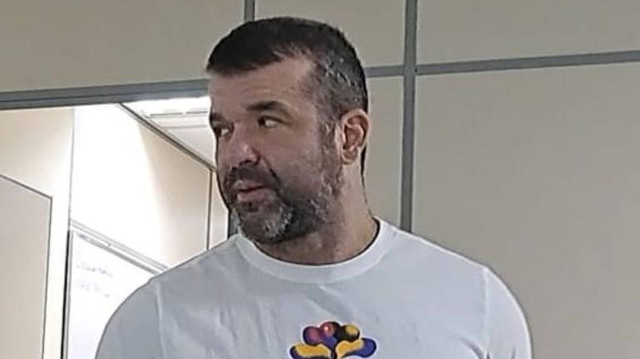 Thiago Brennand olhando para o lado com expressão séria, vestindo camiseta branca estampada