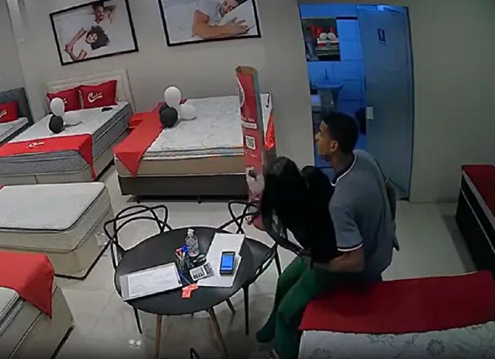 Homem tentando imobilizar vendedora em loja de colchão