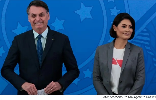 Jair e Michelle Bolsonaro sorrindo lado a lado, em pé