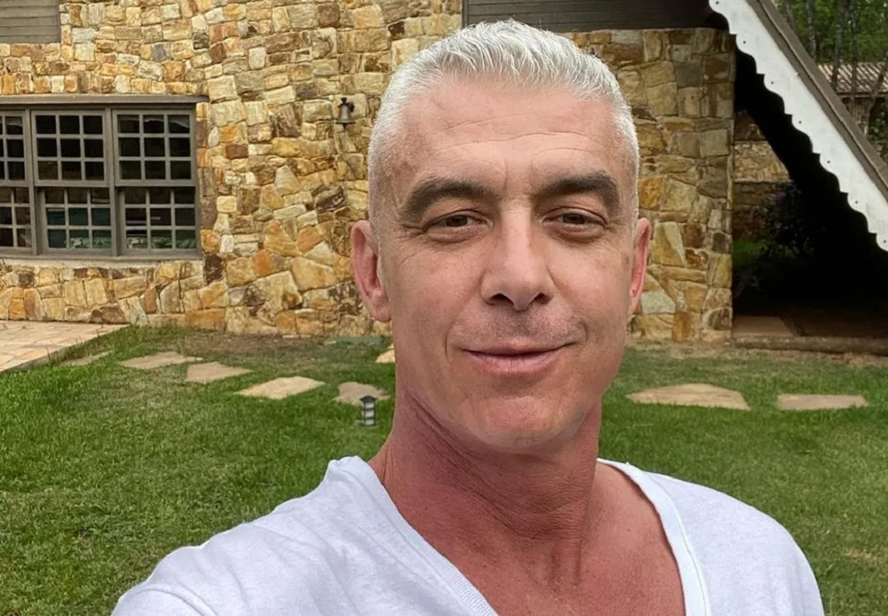 Alexandre Correa com sorriso tímido e blusa branca