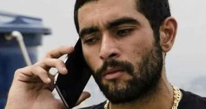 Marcos Antônio da Silva Junqueira de roupa preta, falando ao celular com expressão séria
