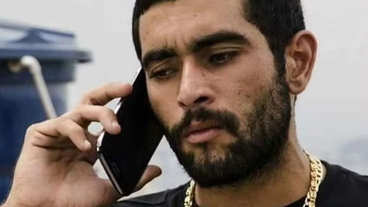 Marcos Antônio da Silva Junqueira de roupa preta, falando ao celular com expressão séria