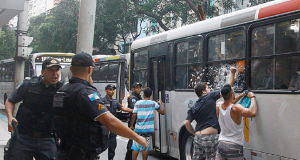 Policiais discutindo perto de homens olhando para dentro de ônibus