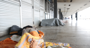 Pessoa em situação de rua dormindo coberta, pé em destaque
