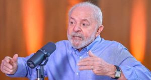 Lula falando em microfone e gesticulando, com roupa social azul e expressão séria