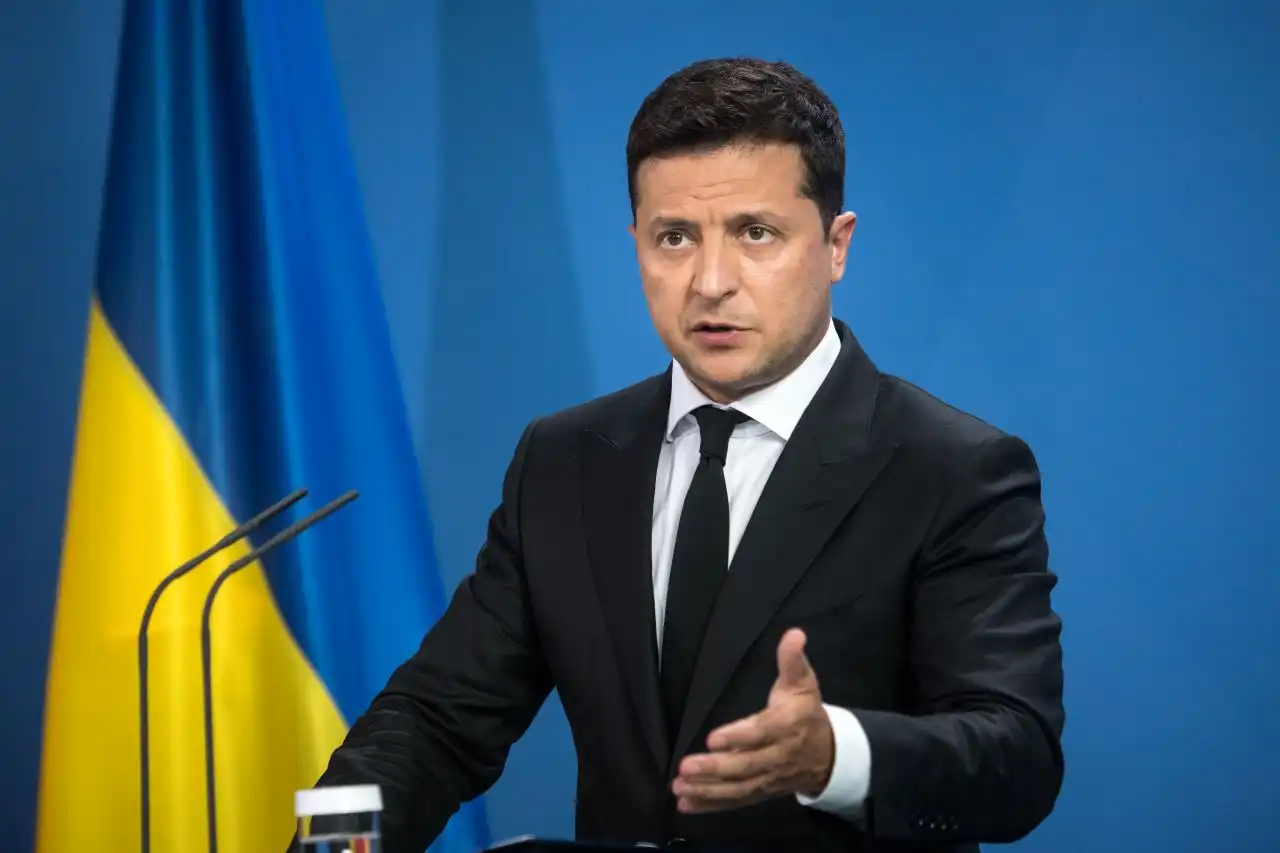 Volodymyr Zelensky falando e gesticulando, com expressão séria