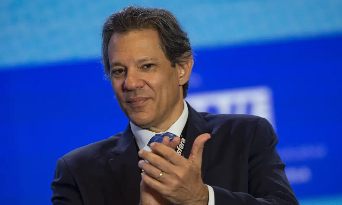 Fernando Haddad batendo palmas, com sorriso tímido