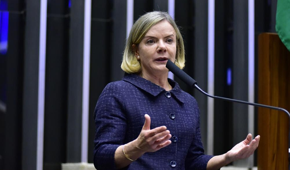 Gleisi falando e gesticulando, de roupa escura e cabelo solto