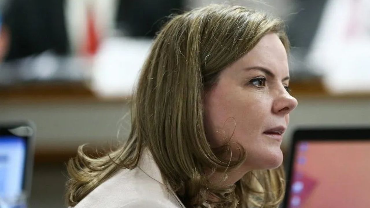 Gleisi Hoffmann de cabelo solto, de perfil, falando com expressão séria