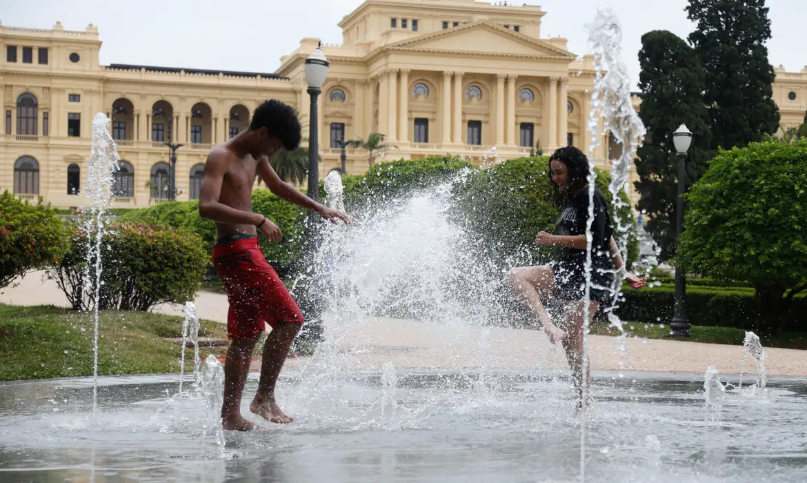 Crianças se refrescando em chafariz