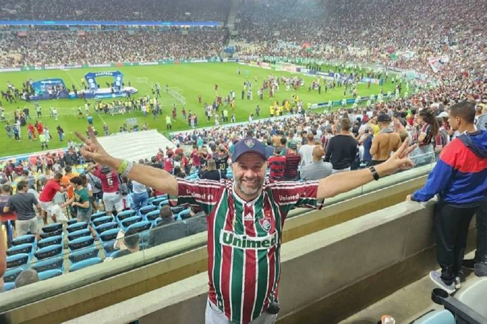 Lupi com camisa do Fluminense, sorrindo com braços abertos em estádio