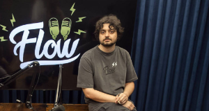 Monarka apoiado em mesa com roupa cinza, no estúdio do Flow
