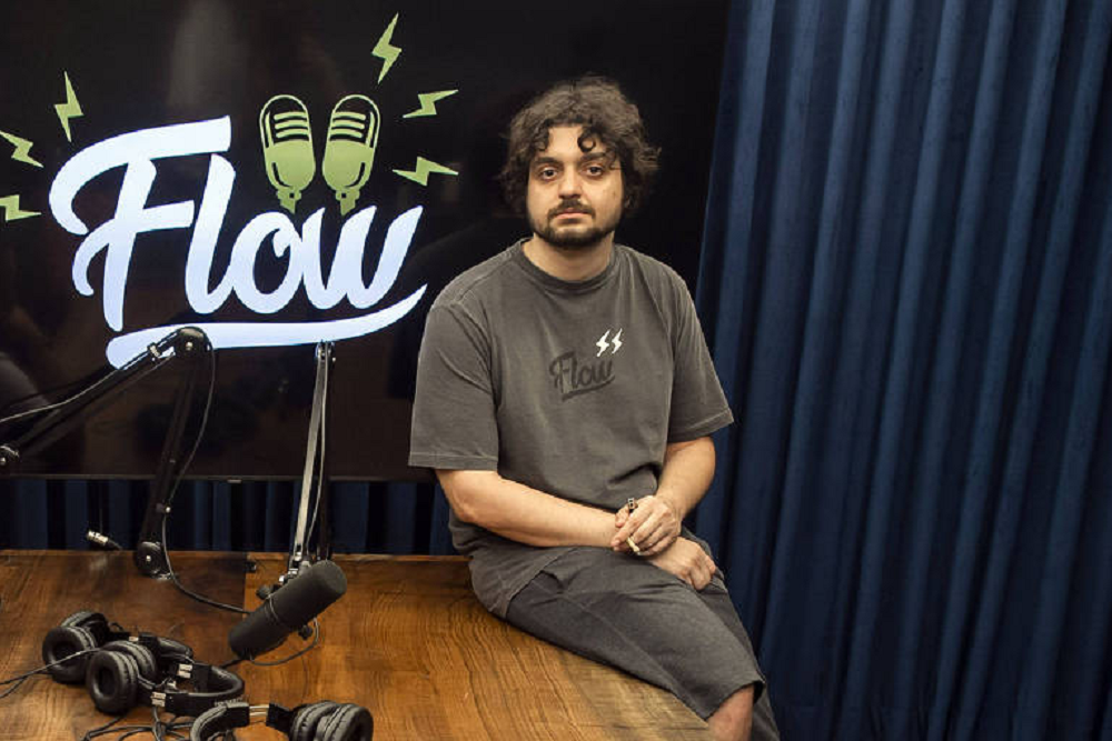 Monarka apoiado em mesa com roupa cinza, no estúdio do Flow