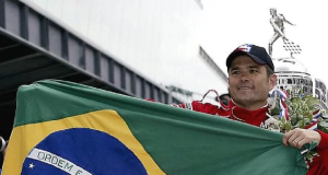 Gil de Ferran segurando bandeira do Brasil, de roupa de corrida