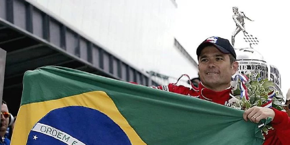 Gil de Ferran segurando bandeira do Brasil, de roupa de corrida